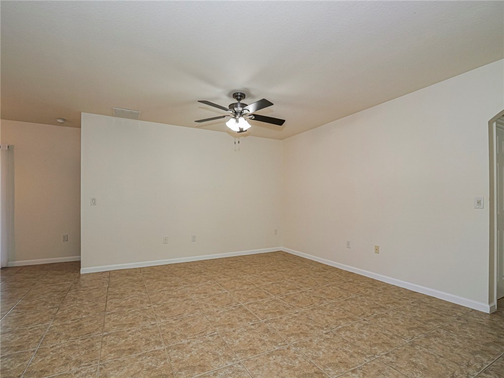 Spacious room featuring tile flooring, neutral wall tones, and a ceiling fan with integrated lighting