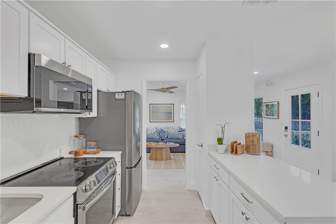 Kitchen featuring appliances with stainless steel finishes, white cabinetry, backsplash, light wood-type flooring, and recessed lighting