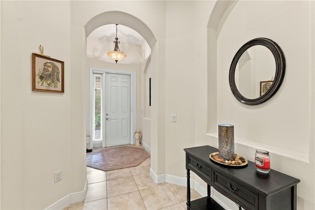Arched entryway featuring a tile floor, decorative lighting, and a paneled entry door with sidelight