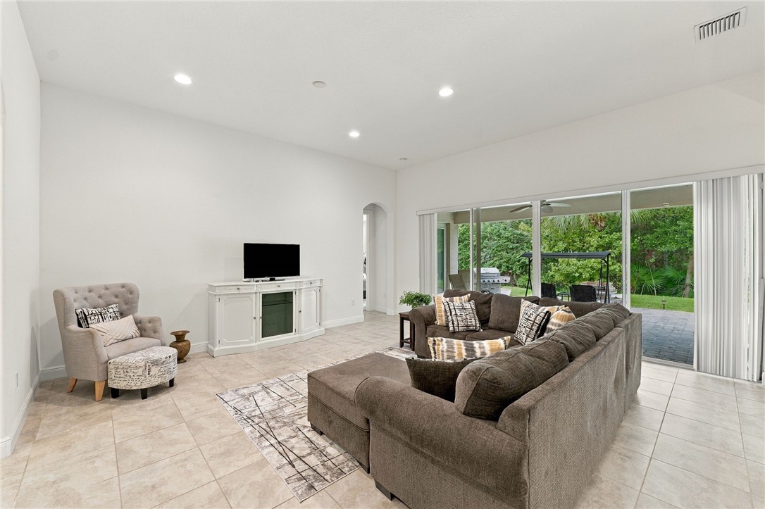 Neutral-toned tile flooring, recessed ceiling lighting, arched doorway, and sliding glass doors opening to outdoor space