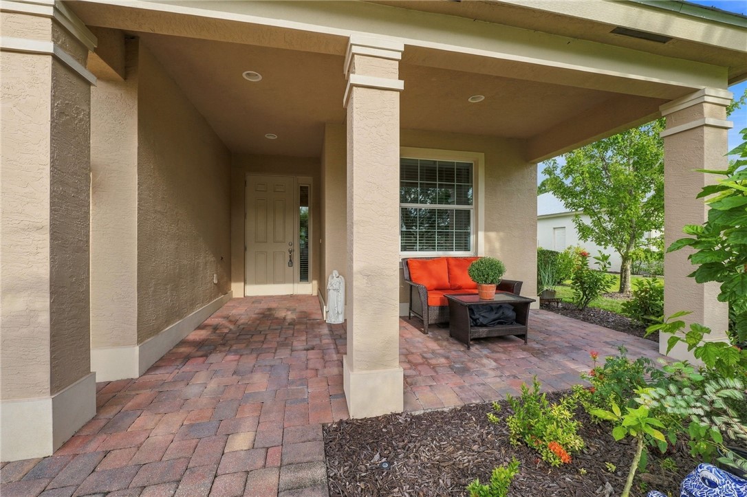 Covered entryway featuring brick pavers, a paneled entry door with sidelight, and recessed lighting