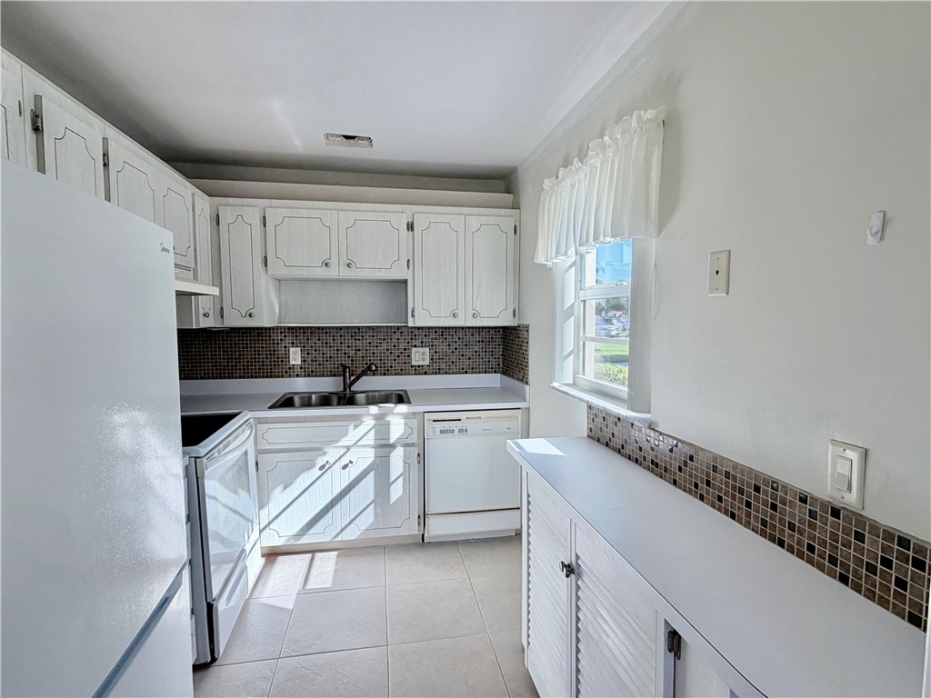Kitchen with white cabinetry, tile flooring, and a mosaic tile backsplash