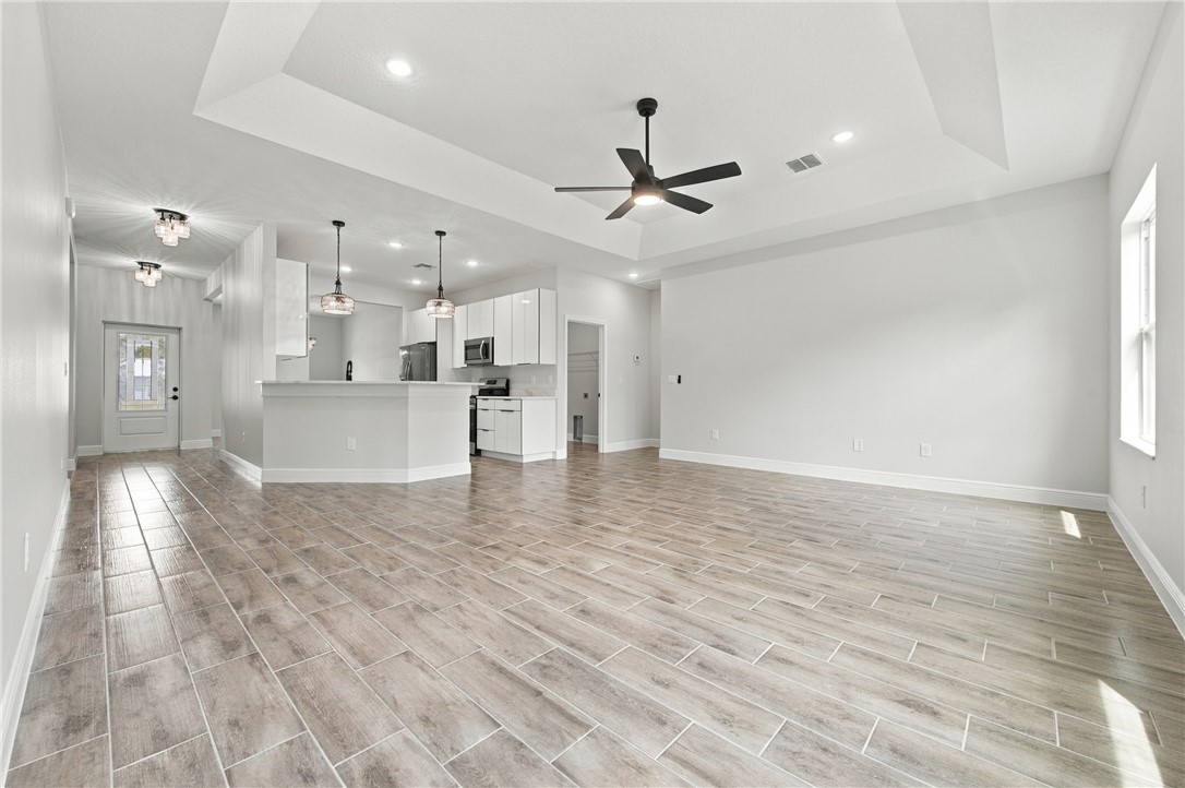 Open-concept living space with wood-finish flooring, a tray ceiling, and recessed lighting