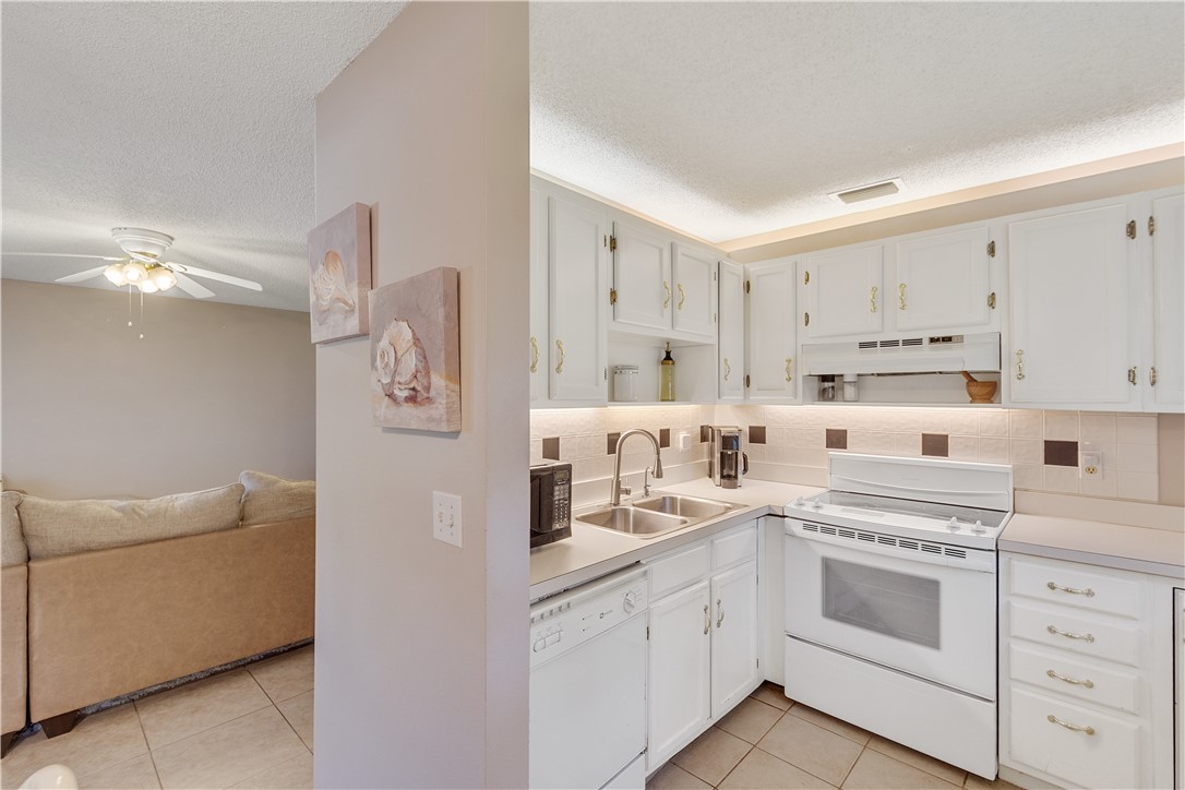 Kitchen featuring white cabinetry, a dual-basin stainless steel sink, tile flooring, and a white oven range