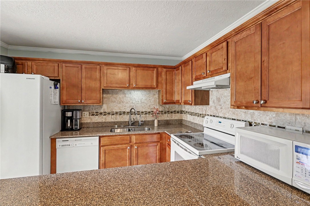 Kitchen featuring wood cabinetry, stone countertops, and a tile backsplash