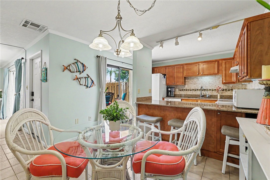 Kitchen featuring wood cabinetry, a tiled backsplash, track lighting, and a breakfast bar with stone-finish countertops