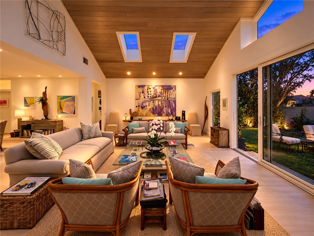 Vaulted wood-finish ceiling with two skylights, recessed lighting, and a prominent glass sliding door opening to a landscaped outdoor area
