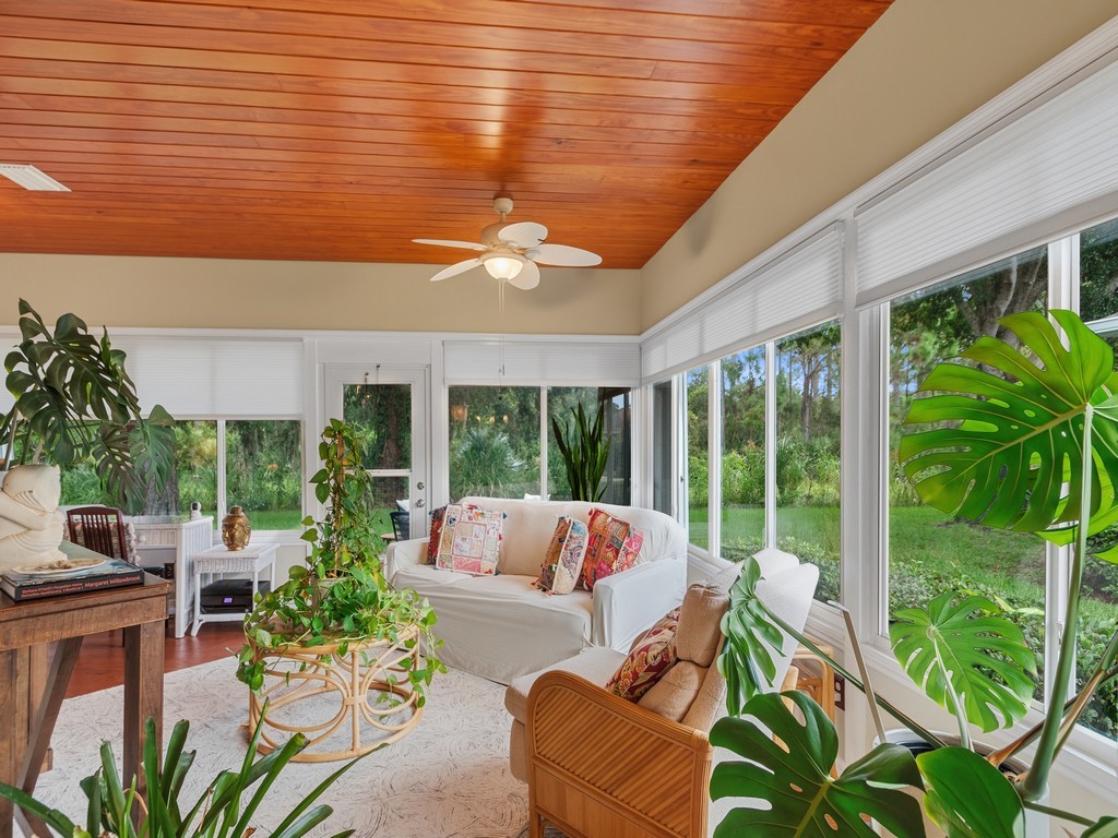 Wood-finish plank ceiling, multiple ceiling fans, full-height windows, and a glass-paneled exterior door