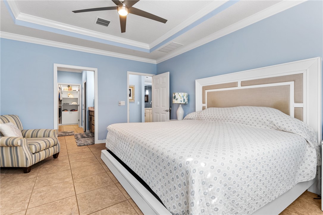 Tray ceiling with crown molding, ceiling fan, and tile flooring