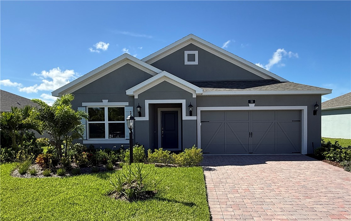 Stucco exterior with contrasting trim, paver driveway, attached two-car garage, and established landscaping