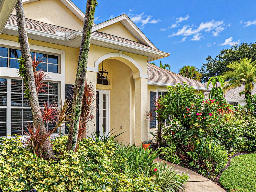 Stucco exterior, arched entry, transom window, architectural shingle roof, mature landscaping