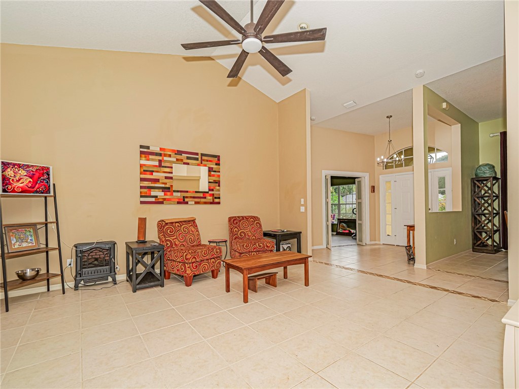 Vaulted ceilings with a ceiling fan, light-toned tile flooring, and a double entry door with transom window