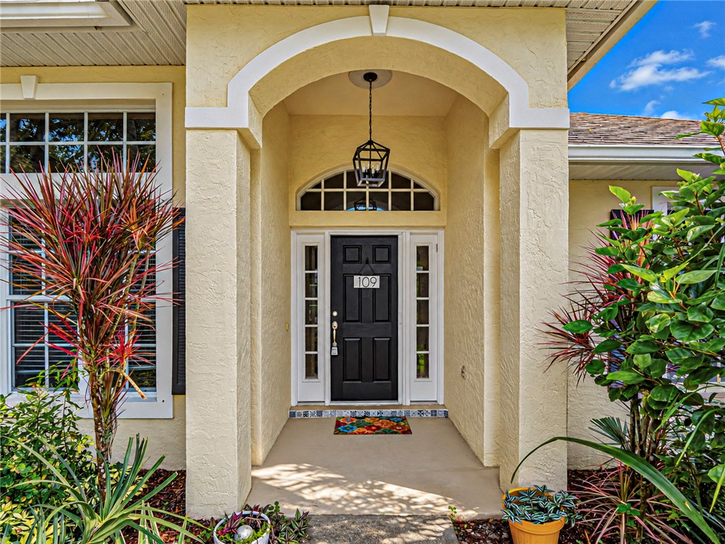 Arched entryway featuring a black front door with sidelights, transom window, and an overhead lantern-style light fixture