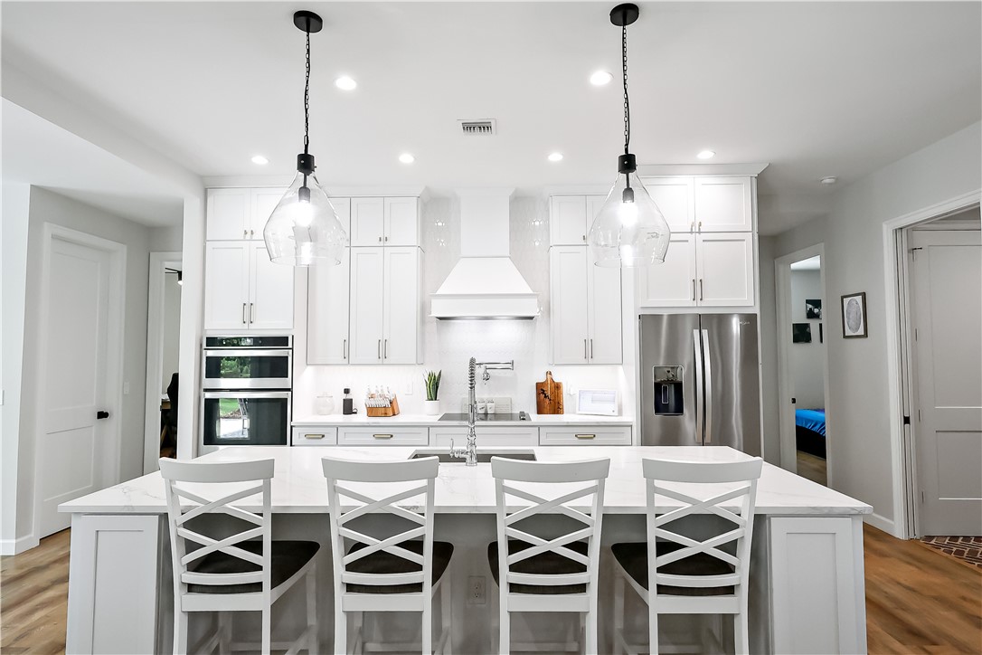 Contemporary kitchen with white cabinetry, stainless steel appliances, a center island with seating, and recessed lighting