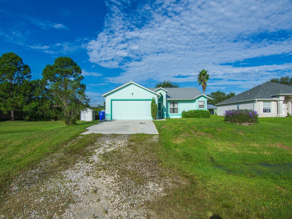 Single-story residence with a light green exterior, an attached garage, and a gravel driveway