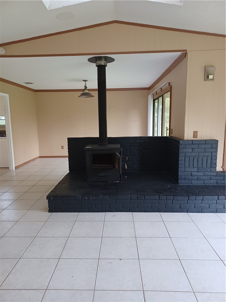 Black brick hearth with a wood-burning stove, white tile flooring, and a sliding glass door