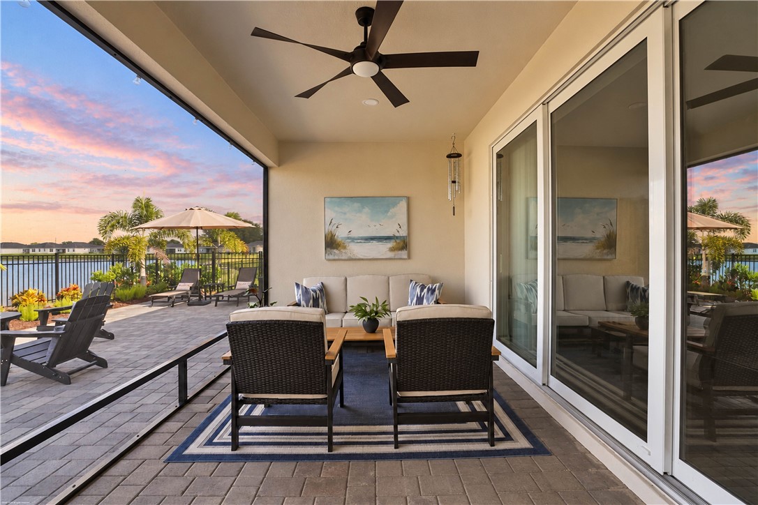Covered patio with paver flooring, multiple sliding glass doors, and a ceiling fan