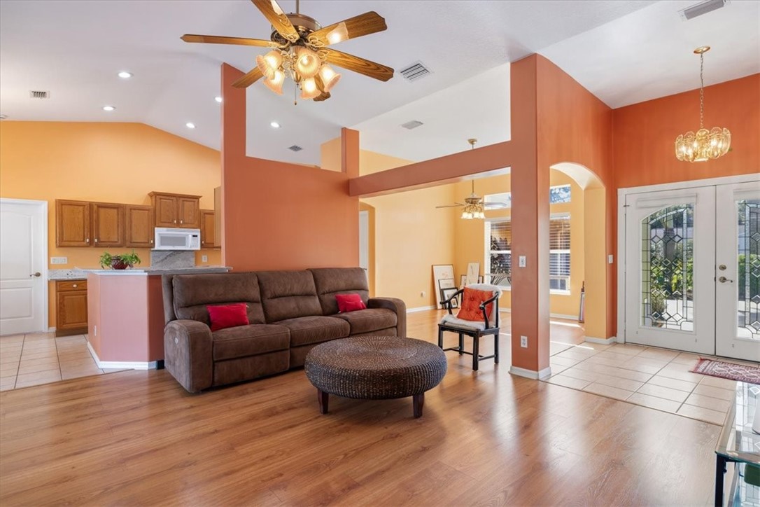 Vaulted ceilings, wood-finish flooring, kitchen with wood cabinetry and a breakfast bar, and double entry doors with decorative glass
