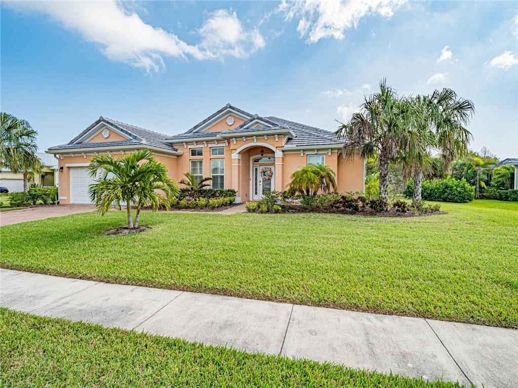 View of front facade featuring a front lawn, stucco siding, an attached garage, and driveway