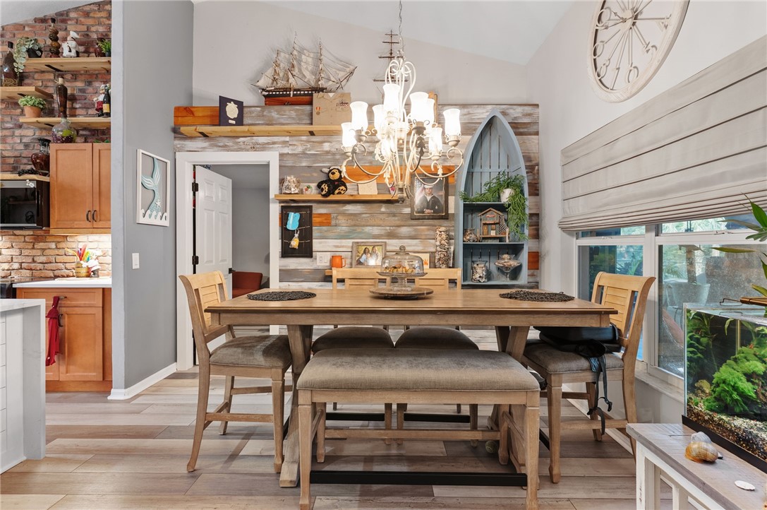Vaulted ceiling, wood-finish flooring, recessed lighting, white window frames, and horizontal window blinds