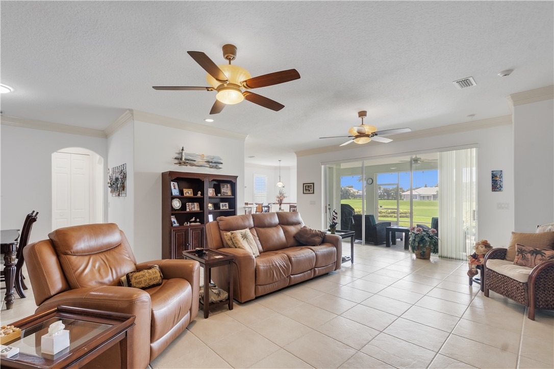 Tiled flooring, multiple ceiling fans, arched doorway, and expansive sliding glass doors opening to an outdoor living area