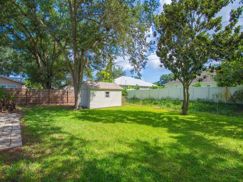 Back yard with utility shed
Expansive green lawn, mature trees, wood privacy fence, chain link fence, and a detached storage shed
