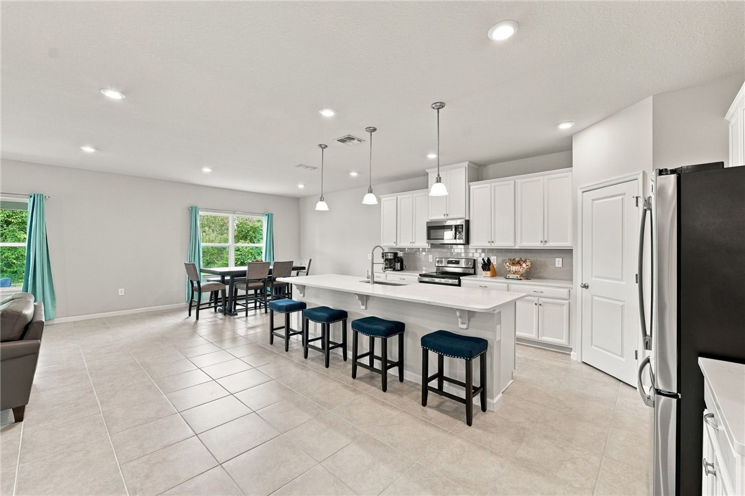 Open-concept living space with tile flooring, recessed lighting, and a kitchen island featuring pendant lighting