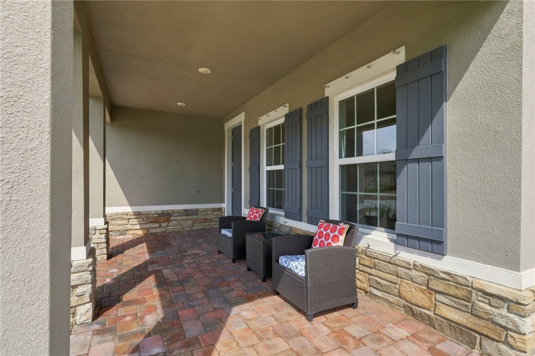 Covered porch featuring a paver flooring, stone accent wall, recessed lighting, and board-and-batten shutters