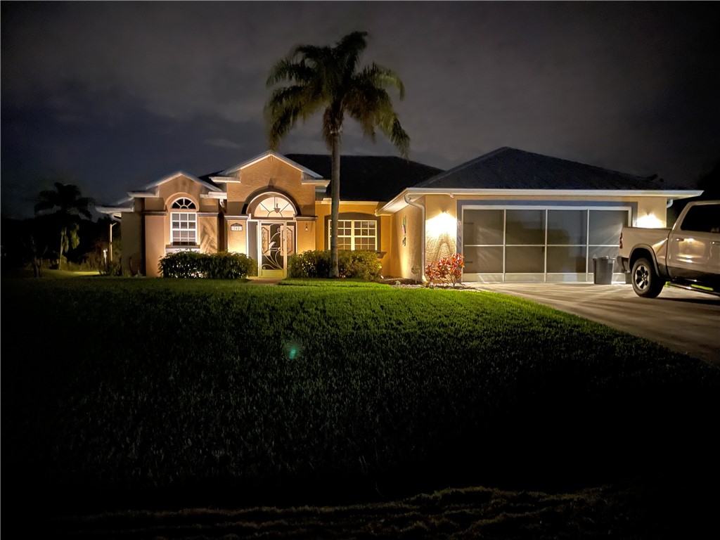 Stucco exterior with arched entry, decorative front door, transom window, and a paneled garage door