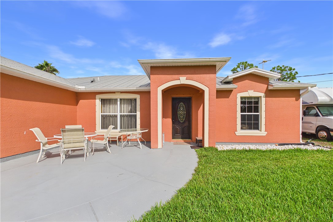 Exterior stucco finish with a metal roof and an arched entryway