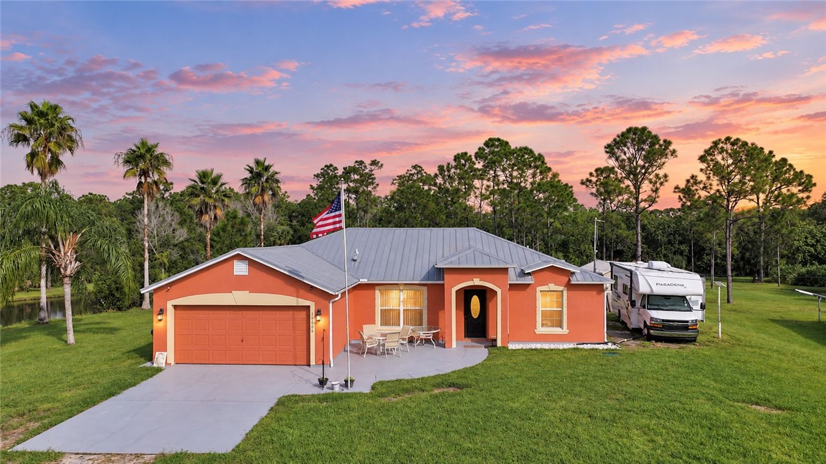 Single-story residence featuring a metal roof, attached garage, curved concrete driveway, and a front patio area