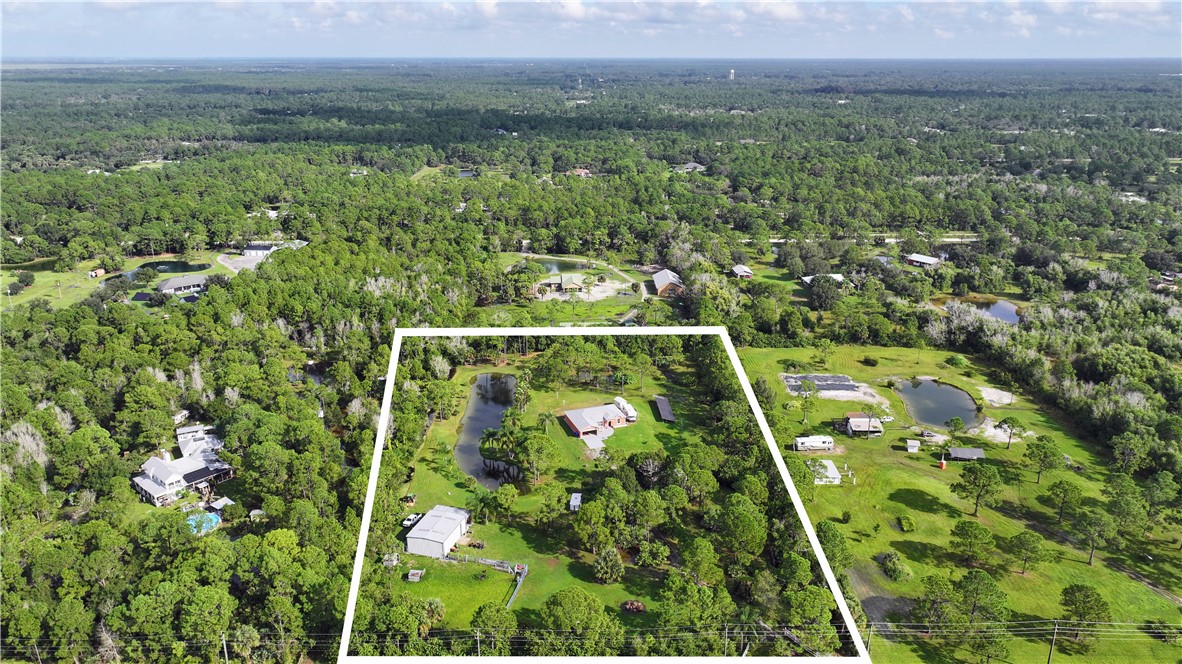 Expansive wooded acreage featuring a main residence, additional structure, and a private pond