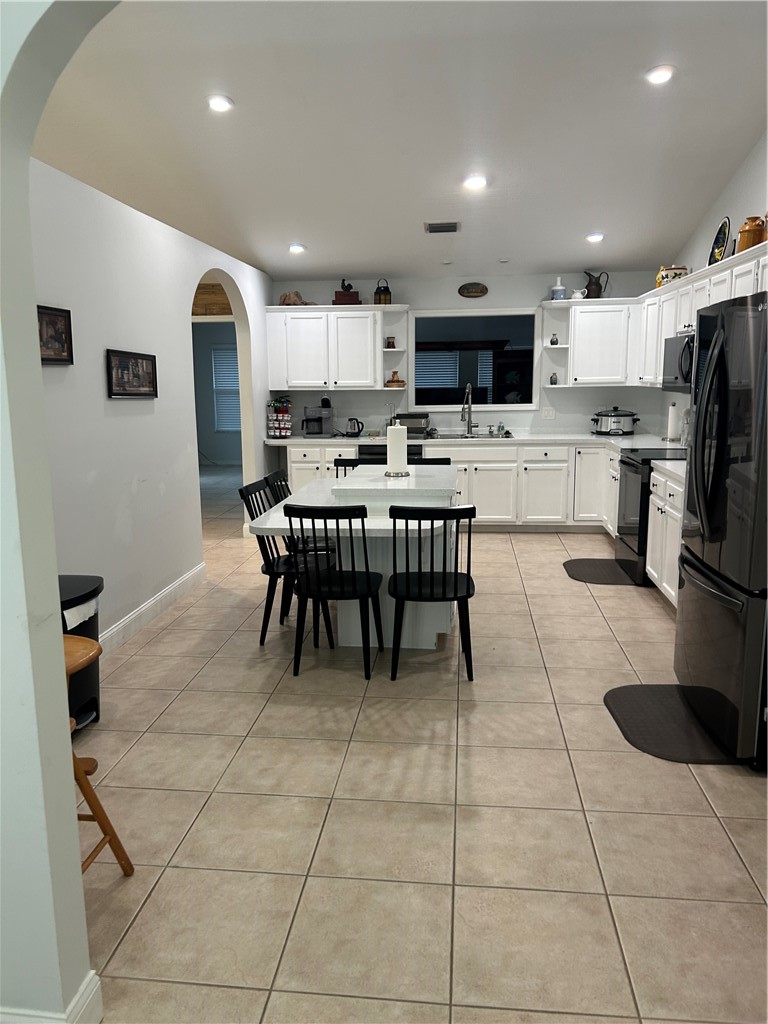 Kitchen featuring recessed lighting, tile flooring, white cabinetry, a kitchen island, and a stainless steel sink