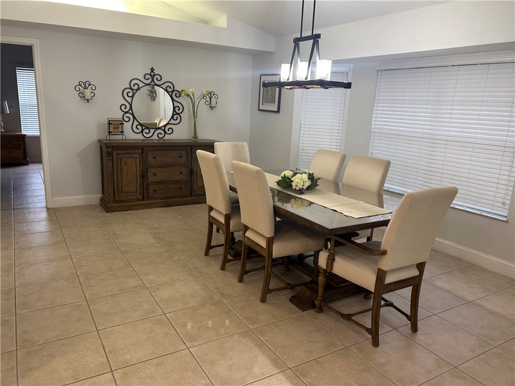 Recessed ceiling with an overhead light fixture, tile flooring, and multiple windows with blinds