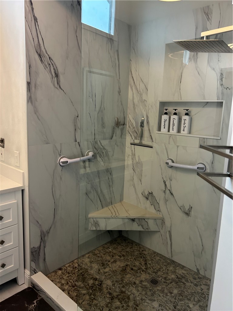 Shower enclosure featuring white marble-look wall tiling, a built-in corner bench, and a built-in shower niche