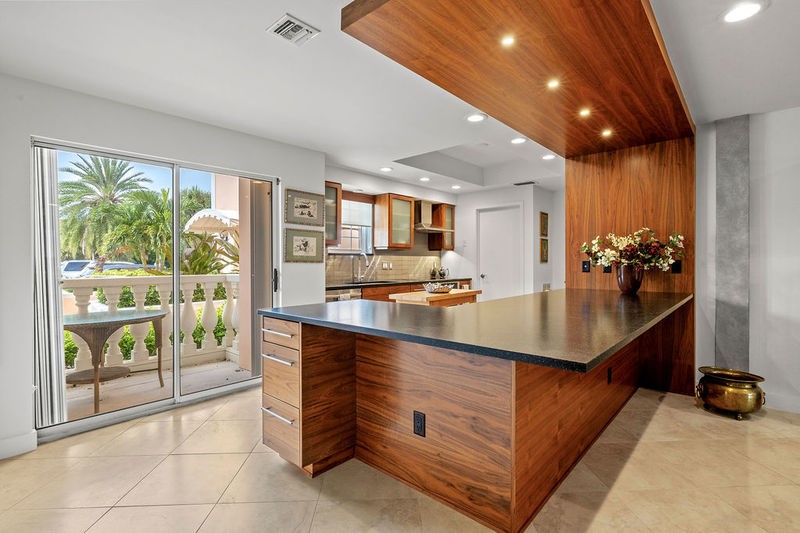 Contemporary kitchen featuring a custom wood-wrapped island with waterfall countertop, professional-grade stainless steel appliances, and warm wood cabinetry