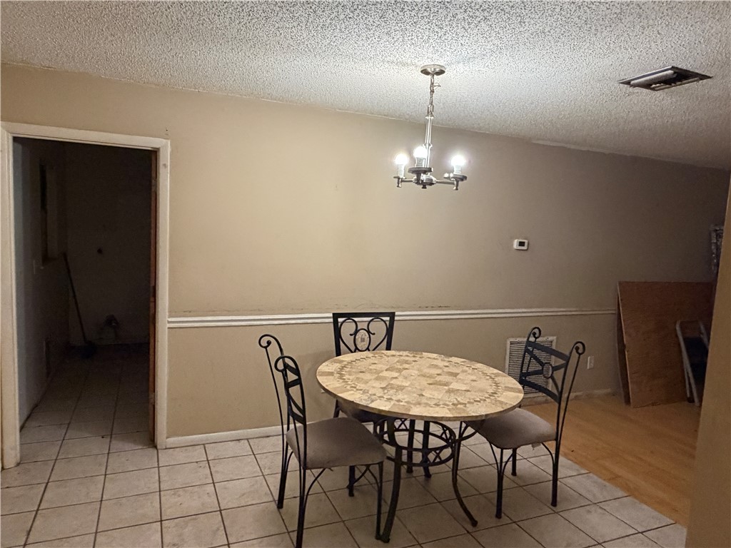 Recessed lighting with a chandelier, two-tone painted walls, and tiled flooring