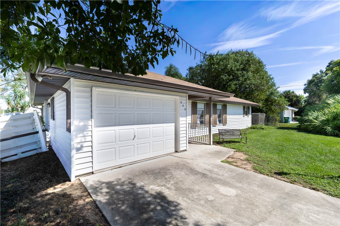 Exterior featuring white horizontal siding, attached single-car garage with white paneled door, concrete driveway, and covered front entry