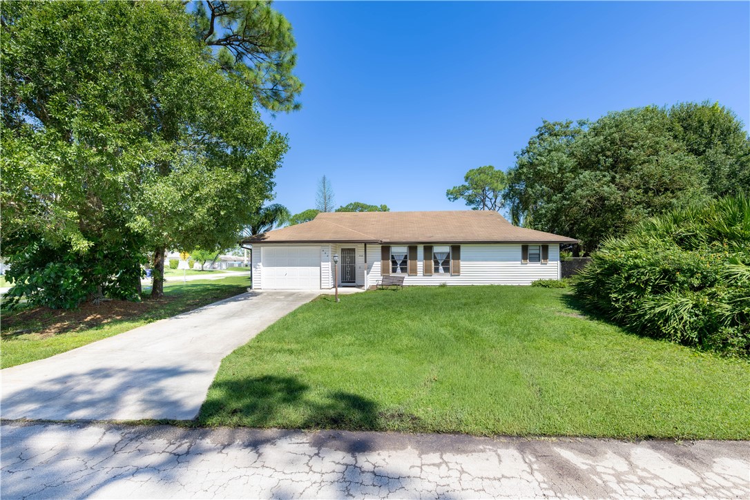 Single-story residence featuring horizontal siding, a hipped roofline, an attached one-car garage, shuttered windows, and mature landscaping