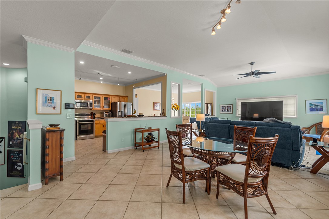 Open-concept floor plan featuring tile flooring, vaulted ceilings, recessed lighting, and a kitchen equipped with built-in cabinetry and stainless steel appliances