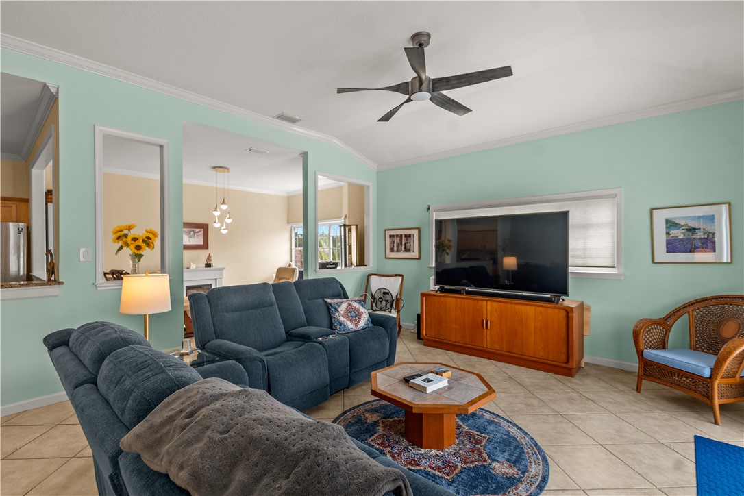 Living room featuring vaulted ceilings, ceiling fan, ceramic tile flooring, and interior wall cutouts