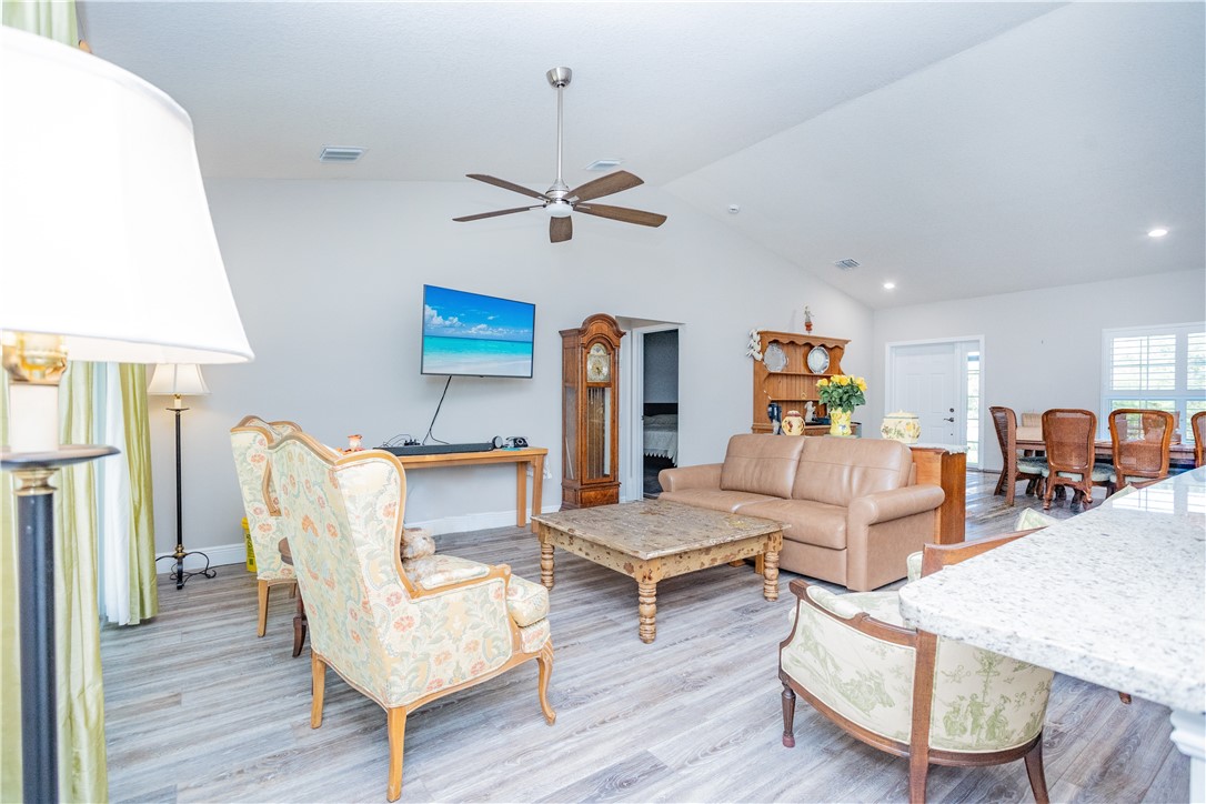 Vaulted ceilings with recessed lighting, wood-finish flooring, and a central ceiling fan