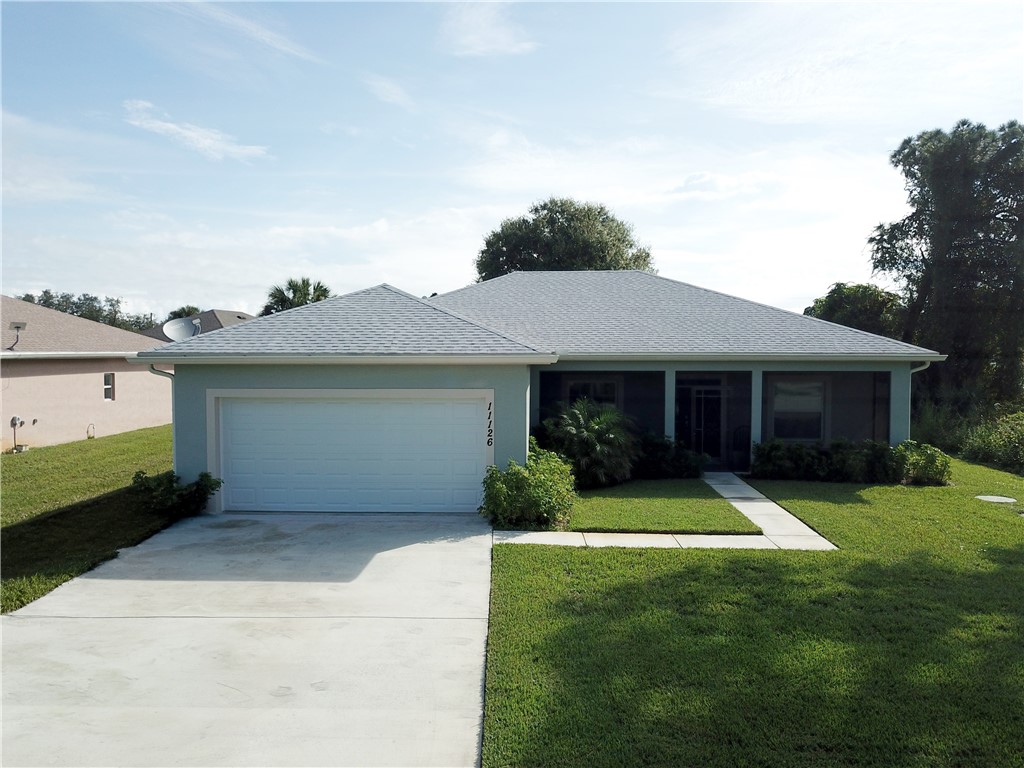 Single-story residence featuring a hip roof, two-car garage, concrete driveway, and a covered entryway with a screened enclosure