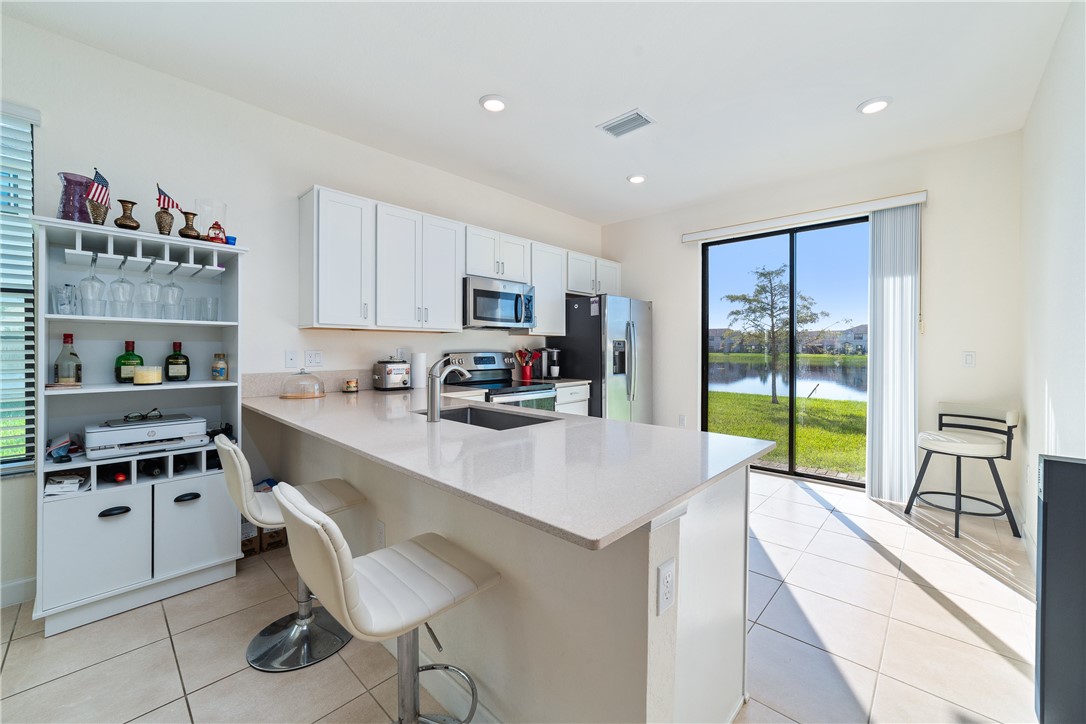 Kitchen featuring white cabinetry, solid-surface countertops, recessed lighting, and a sliding glass door with water scenery