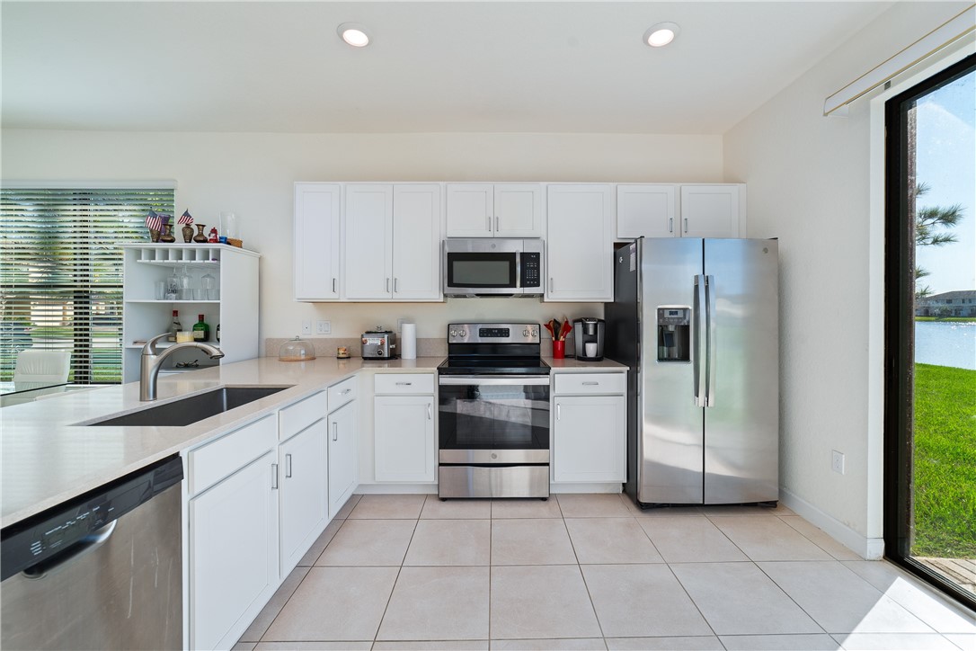 Kitchen featuring white cabinetry, quartz countertops, stainless steel appliances, recessed lighting, and tile flooring