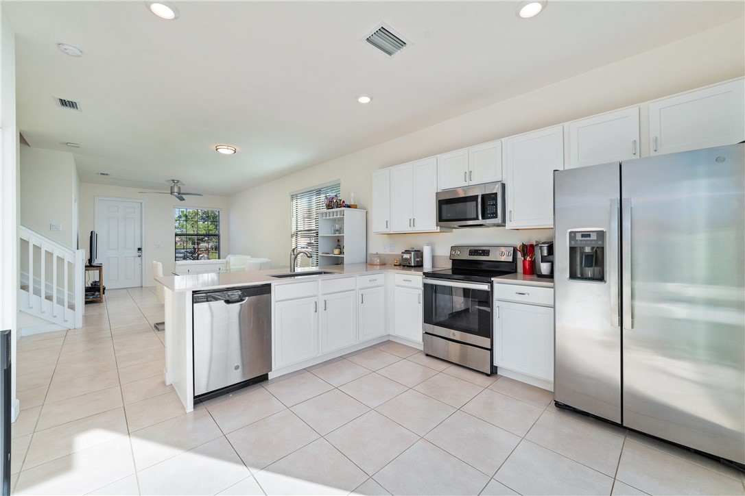 Kitchen featuring white shaker-style cabinetry, stainless steel appliances, tile flooring, recessed lighting, and stone-finish countertops