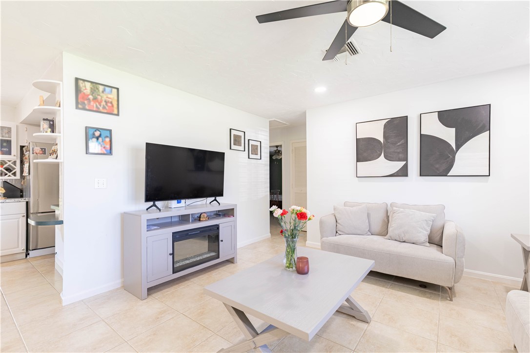Neutral-toned tile flooring, built-in recessed shelving, and a ceiling fan with integrated lighting