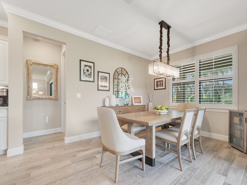 Dining area featuring wood-finish tile flooring, crown molding, a rectangular multi-light pendant fixture, and plantation shutters