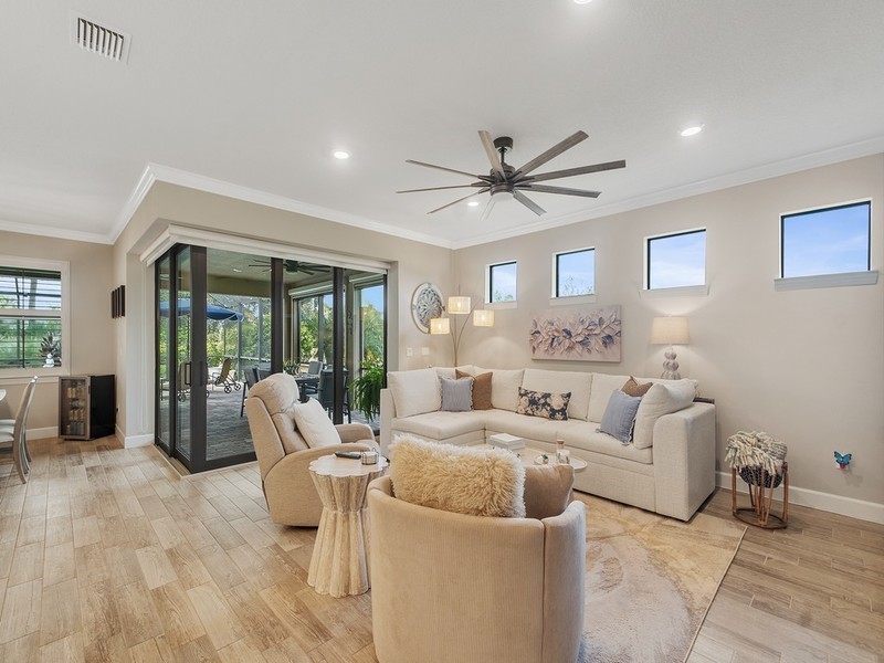 Living area featuring wood-finish tile flooring, recessed lighting, multi-pane transom windows, a multi-blade ceiling fan, and expansive sliding glass doors