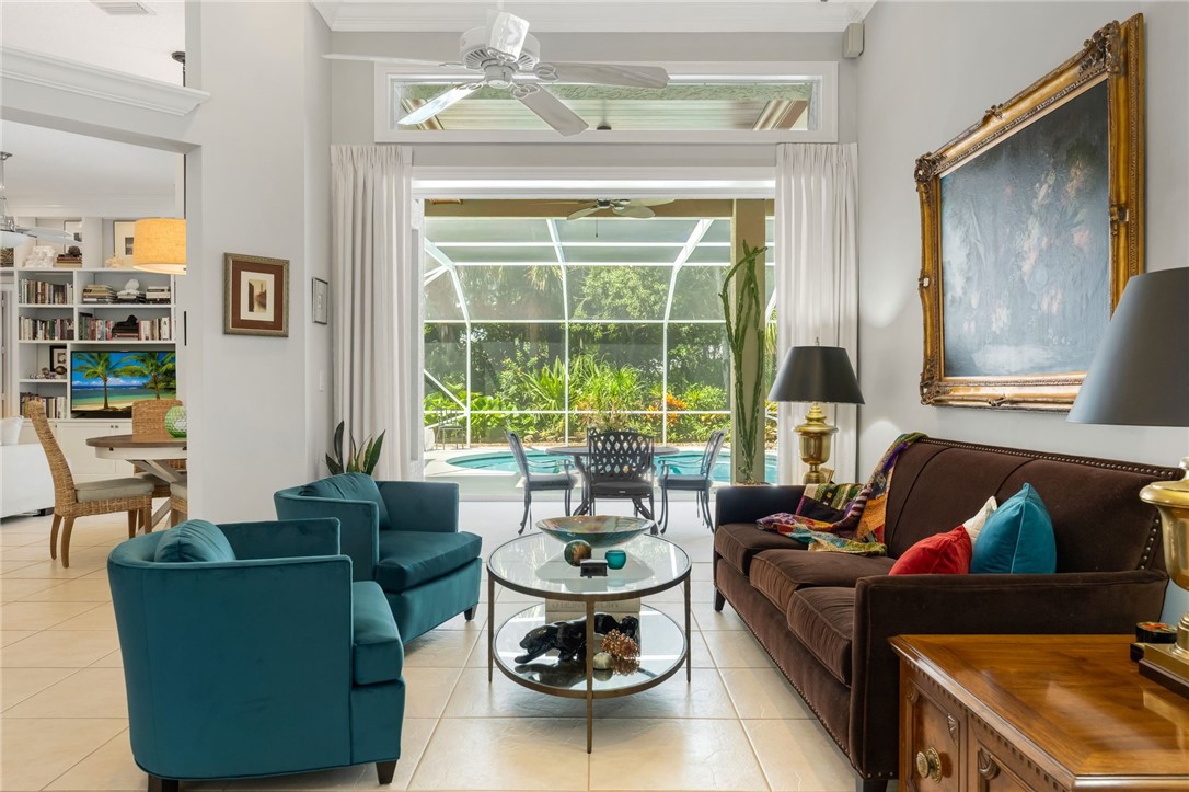 Living room with tile floors and view of kitchen, breakfast nook, outdoor dining area, lanai and heated salt chlorinated pool